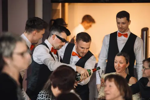 The show waiters pour champagne at a table of guests.