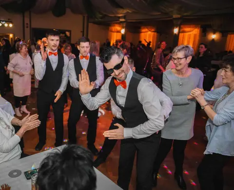 The show waiters dance with laughing guests between the tables.