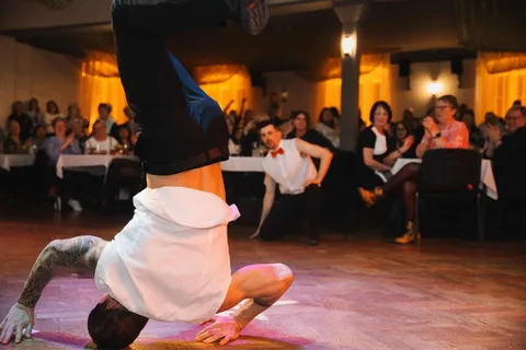 A show waiter performs a headstand in front of guests in the hall.