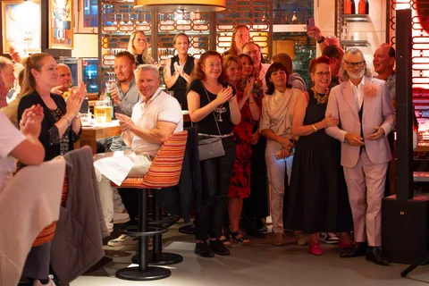 A group of guests applaud and smile after the show in the restaurant.