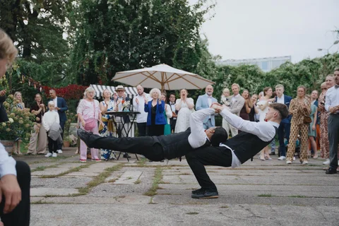 Two show waiters perform partner acrobatics in front of amazed and applauding wedding guests.